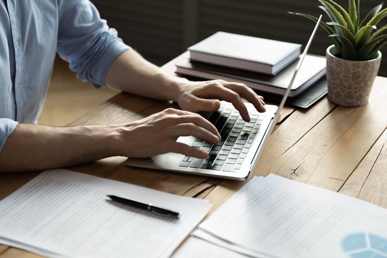 Osoba przy biurku pracuje na laptopie